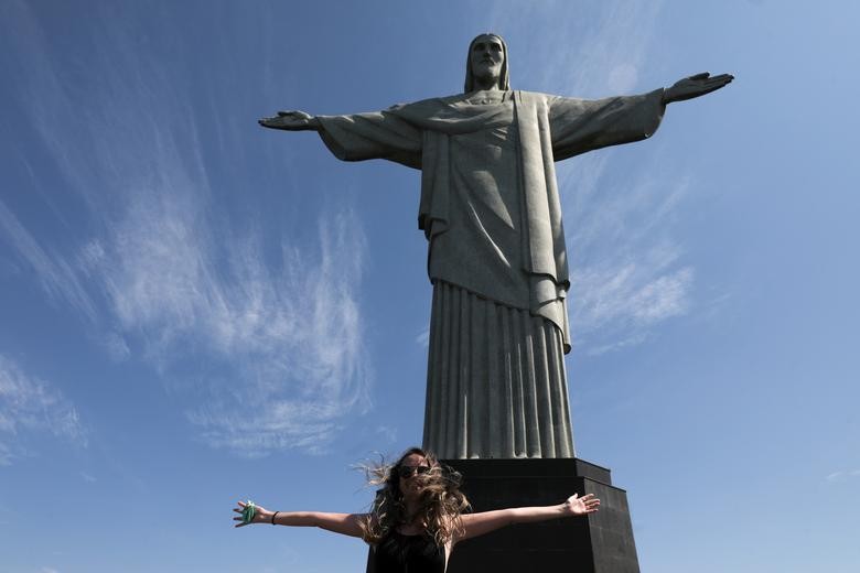 A tourist poses for a picture with open arms during the reopening of the Christ the Redeemer statue after months-long closure due to the outbreak of the coronavirus, in Rio de Janeiro, Brazil.  REUTERS/Pilar Olivares  